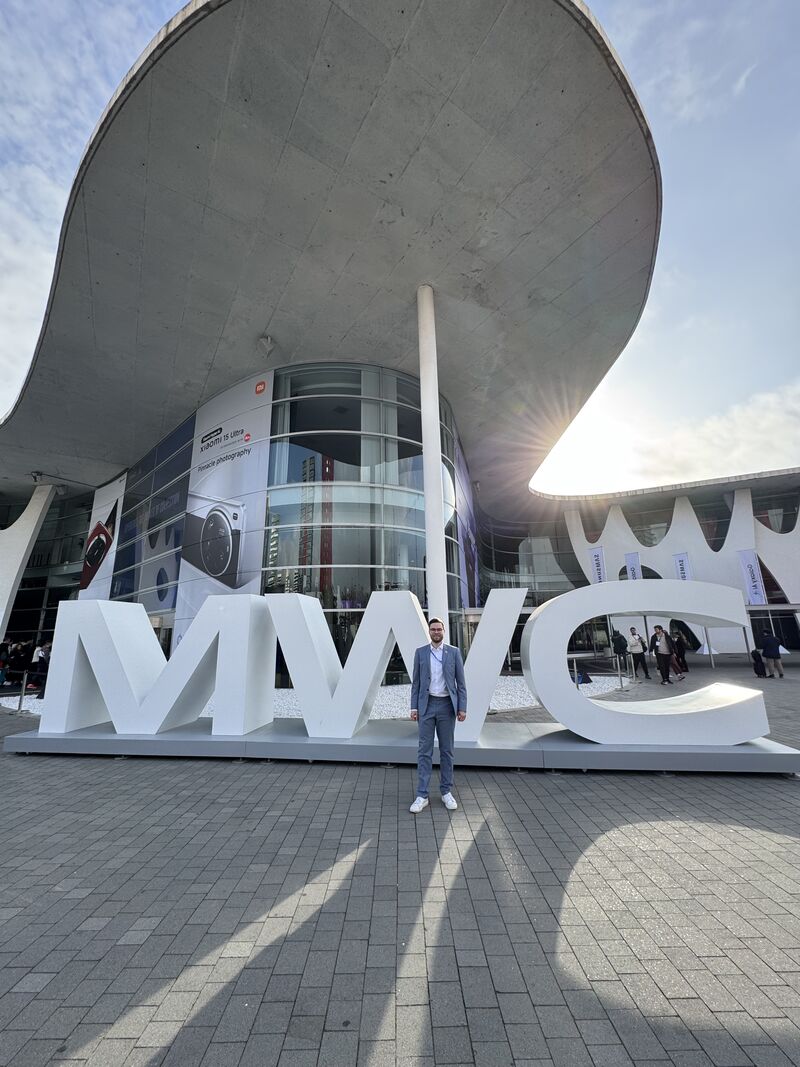 Lauri Alho stands at the MWC 2025 event venue, celebrating a successful week of Network as Code hackathons and remote driving demonstrations.