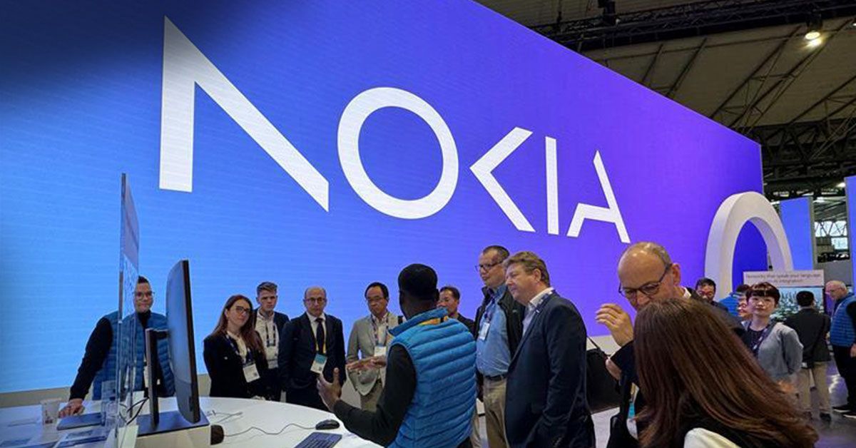 Nokia booth at MWC24 with a large Nokia logo, featuring Lauri Alho and other professionals engaged in discussions and demos of the Network as Code solution.
